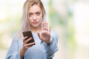 Young Woman Sending Text Message With an Open Hand Doing Stop Sign